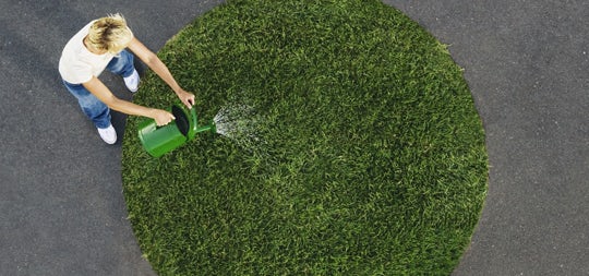 Ariel image of person watering a circle patch of grass.