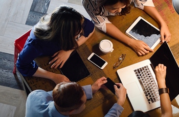 Top down view of a team working in a bright office at a brown table