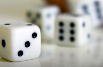 A close-up of white dice with black dots, scattered on a reflective surface, hinting at an ongoing game