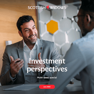 A businessman in a grey suit gestures while discussing in an office setting with a modern design and hexagonal decor