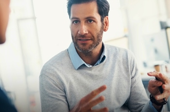 Two people engaged in a serious conversation in a bright, modern office space. One gestures animatedly while speaking