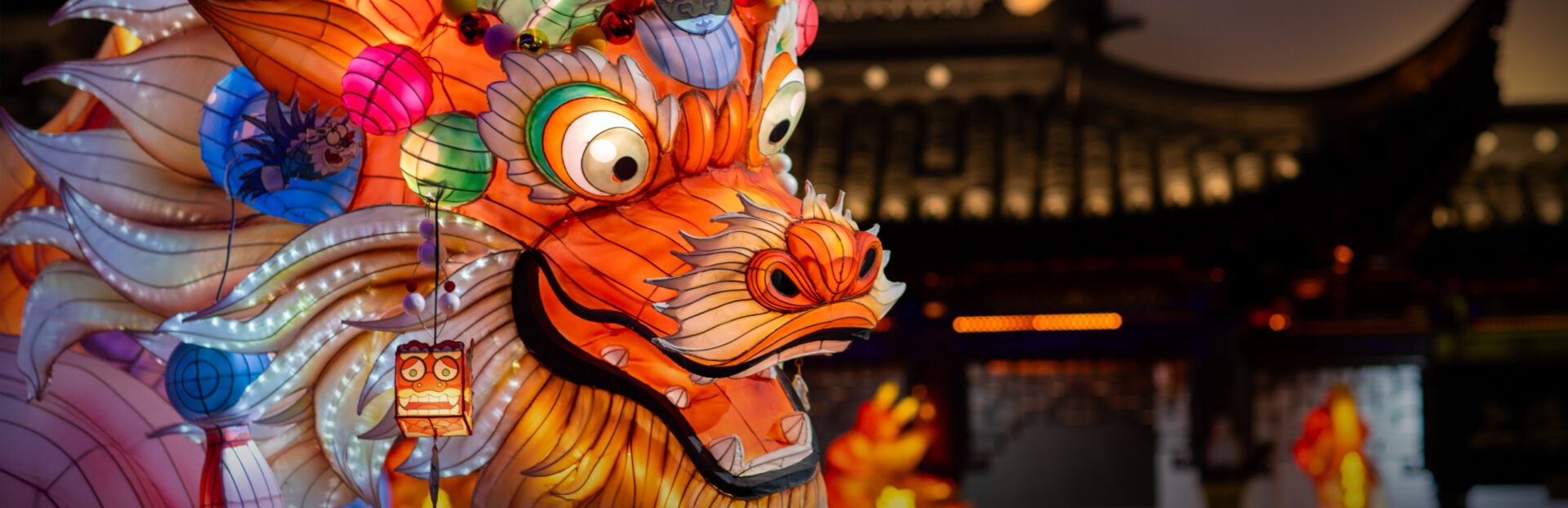 Brightly illuminated dragon lantern adorned with colorful ornaments, capturing the spirit of celebration in a festive venue