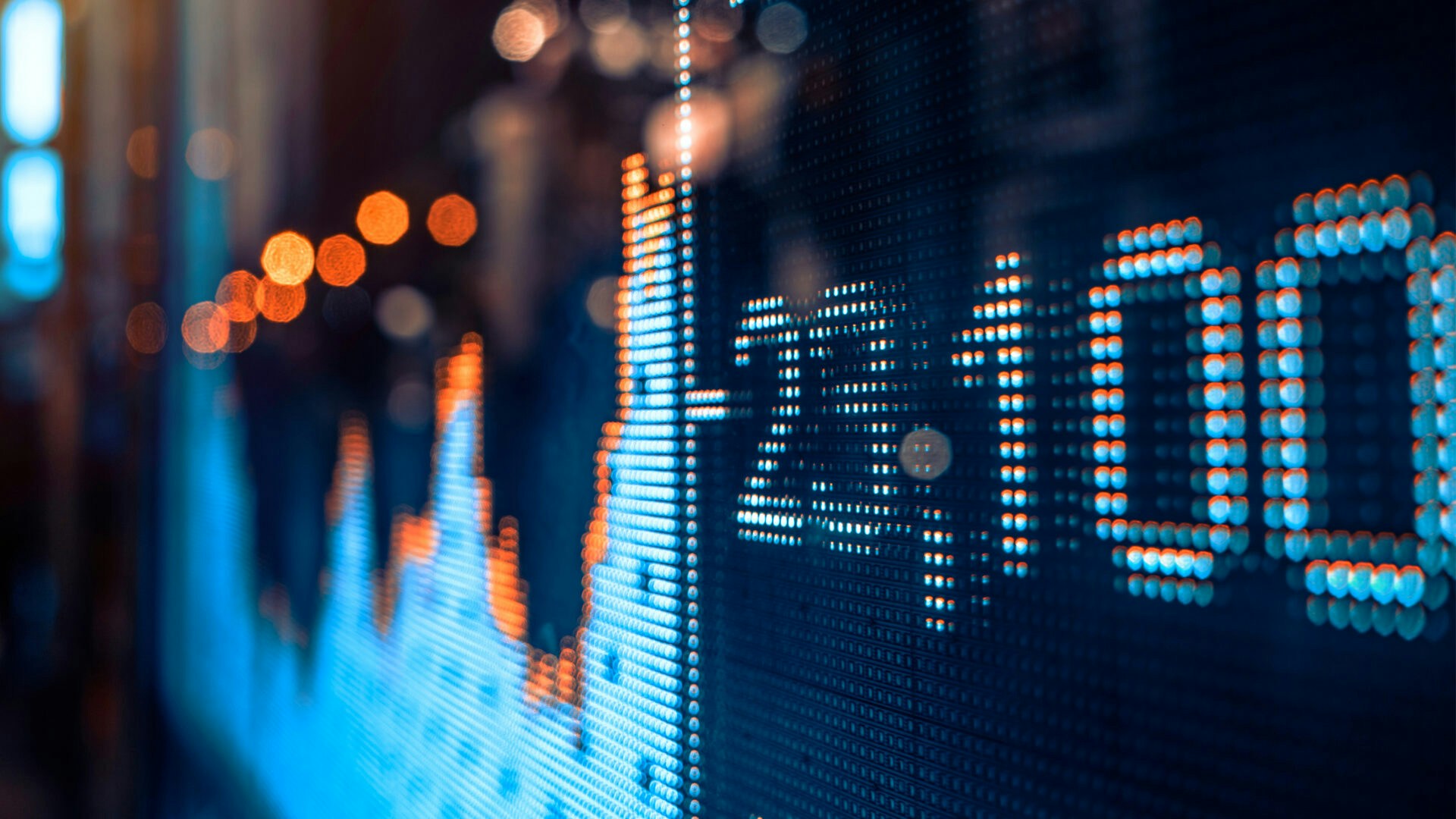 A close-up of a dynamic LED display showing fluctuating stock market statistics, illuminated with vibrant blue and orange lights