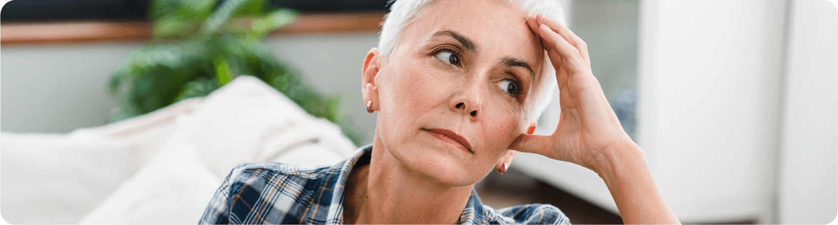 vc-additional-resources-02 A person rests their head on their hand, sitting indoors among soft furnishings and greenery, conveying a moment of contemplation or distress