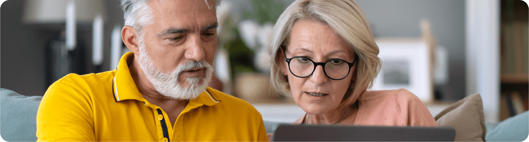 vc-additional-resources-03 A couple sits closely together on a couch, focused on a laptop in a cozy living room setting